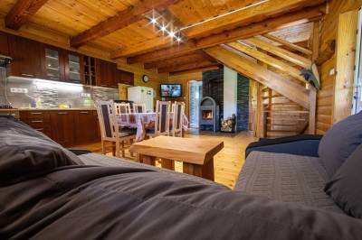 Obývačka s gaučom a kachľami prepojená s kuchyňou, Chata pod Rožkom, Uličské Krivé